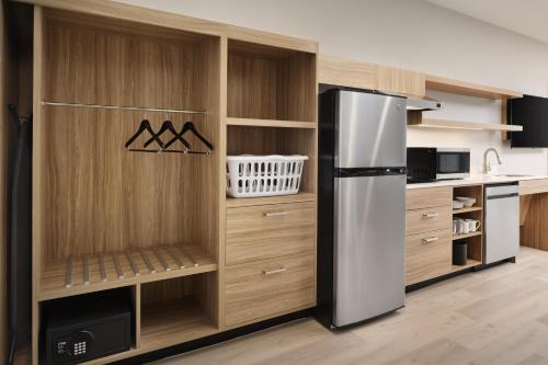 a kitchen with a refrigerator and wooden cabinets at Hyatt Studios Huntsville in Huntsville