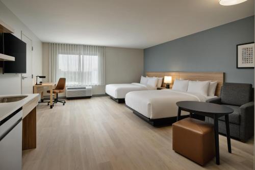 a hotel room with two beds and a couch and a table at Hyatt Studios Huntsville in Huntsville