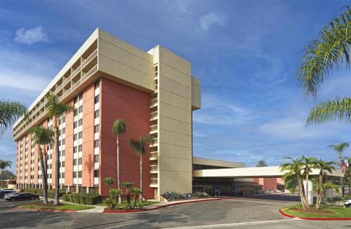 a building with palm trees in front of a parking lot at Ontario Airport Hotel & Conference Center in Ontario