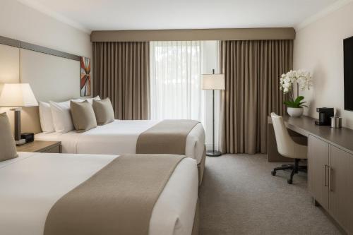 a hotel room with two beds and a desk at Ontario Airport Hotel & Conference Center in Ontario