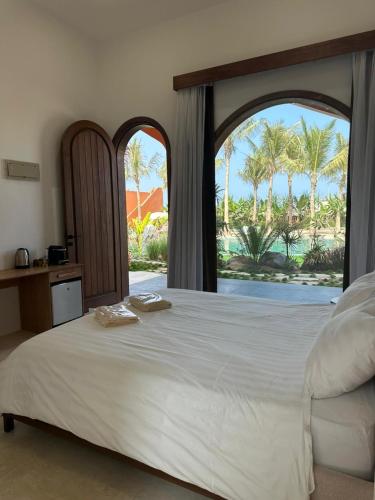 a bedroom with a large white bed and a window at Arabian Coral in Ḩaḑbaram