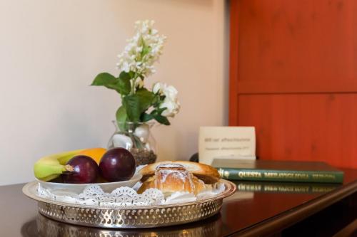 a plate of fruit on a table with a vase of flowers at Affreschi Su Roma Luxury B&B in Rome