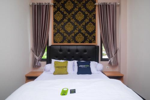 a bedroom with a bed with two pillows and a window at Urbanview Grand Lotus Hotel by RedDoorz in Purwokerto