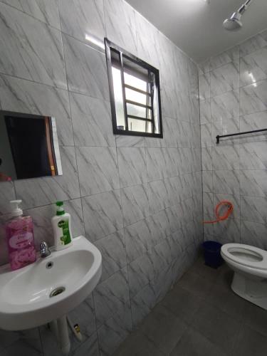a bathroom with a sink and a toilet and a window at FAs KLIA Guesthouse, 4BR 4 AC , NEAR KLIA, NILAI in Sepang