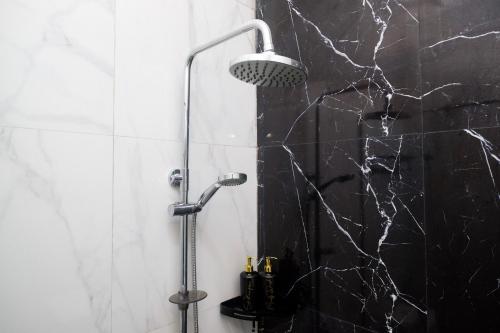 a shower in a bathroom with a black marble wall at Urbanview Grand Lotus Hotel by RedDoorz in Purwokerto