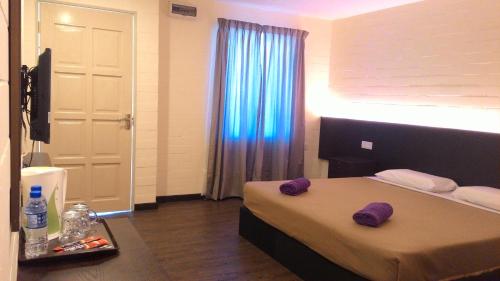 Un dormitorio con una cama con toallas moradas. en Sayy Haa Inn, en Pantai Cenang