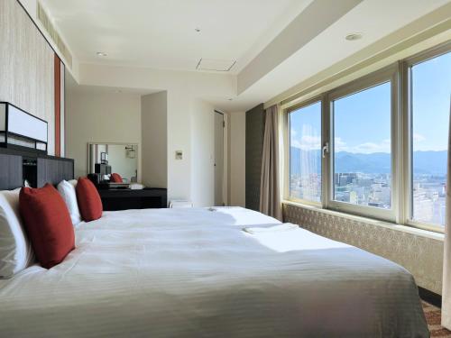 a bedroom with a large bed with a large window at Hotel JAL City Nagano in Nagano