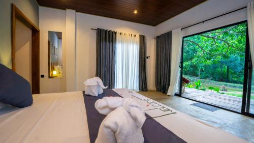 a bedroom with two towels on a bed with a window at Vilona Nature Villa in Dambulla