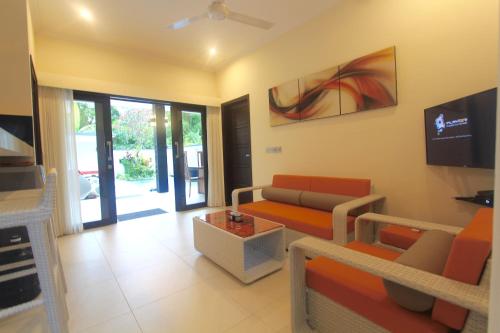 a living room with a couch and a tv at Villa 2Brook in Lovina