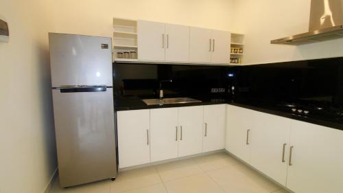 a kitchen with white cabinets and a stainless steel refrigerator at Villa 2Brook in Lovina