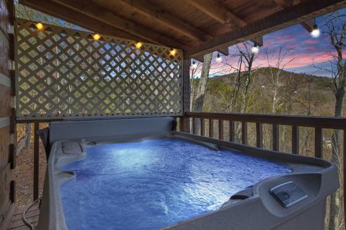 a hot tub on a deck with a fence at Somewhere In Time cabin in Sevierville