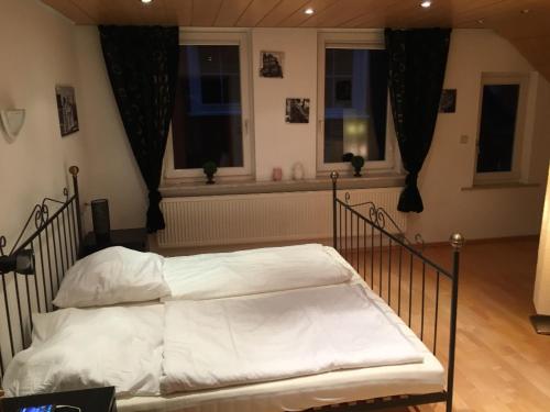 ein Bett mit weißer Bettwäsche in einem Schlafzimmer mit Fenstern in der Unterkunft Ferienwohnung im Herzen Bad Wildbads in Bad Wildbad