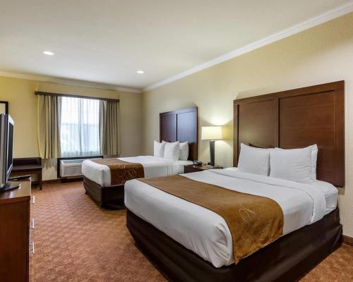 a hotel room with two beds and a flat screen tv at Comfort Suites near NASA - Clear Lake in Webster
