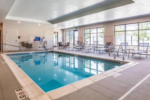 a swimming pool with tables and chairs in a building at Comfort Inn & Suites Salt Lake City Airport in Salt Lake City