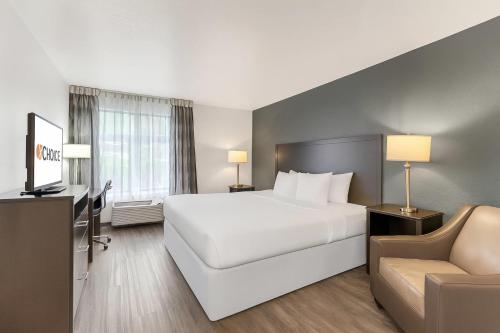 a hotel room with a large white bed and a chair at Clarion Inn Salt Lake City Airport in Salt Lake City