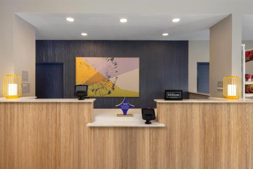 a lobby with a reception desk with a painting on the wall at Spark by Hilton El Paso University in El Paso