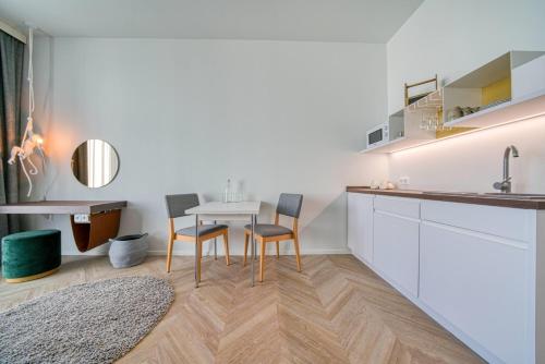 a kitchen with white cabinets and a table and chairs at Vienna House Easy by Wyndham Augsburg in Augsburg