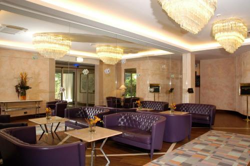 a restaurant with purple chairs and tables and chandeliers at Hotel Donatello Imola in Imola
