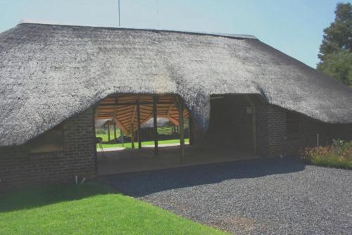 a brick building with a thatched roof at African Flair Country Lodge in Piet Retief
