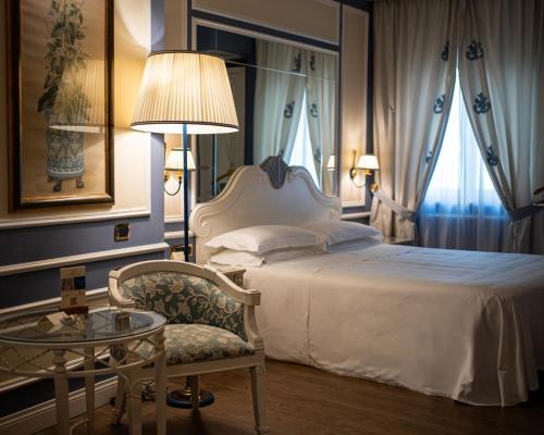 a bedroom with a bed and a chair and a table at Palazzo Alabardieri in Naples