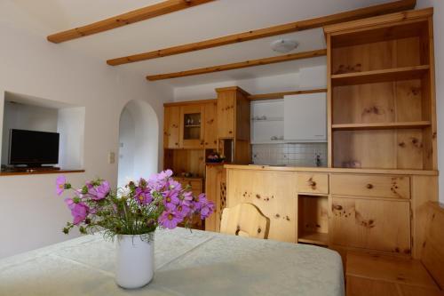 a vase with purple flowers on a table in a kitchen at Residence Kampidell in Siusi