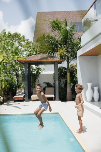 two young boys jumping into a swimming pool at Emerald Villas by Paje Emerald Escapes Ltd in Paje