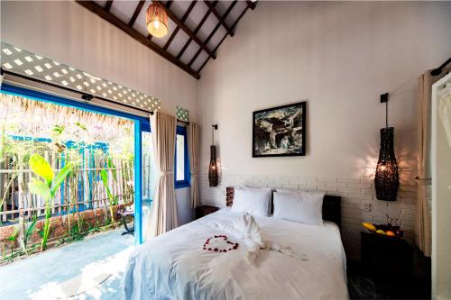 a bedroom with a bed and a large window at Cashew Tree Bungalow in Hoi An