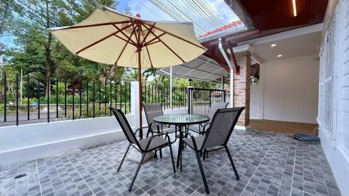 a table with chairs and an umbrella on a patio at Secret Valley near Phuket Town in Kathu