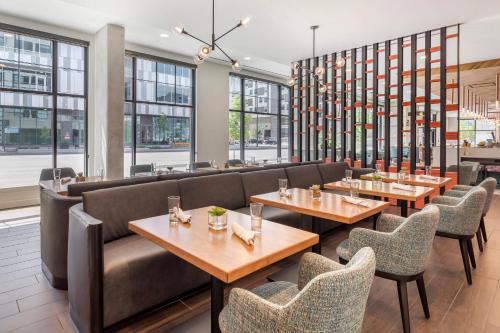 a restaurant with tables and chairs and windows at Cambria Hotel Denver Downtown RiNo in Denver