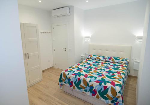 a white bedroom with a bed with a colorful comforter at Apartamento Terra in Benajarafe