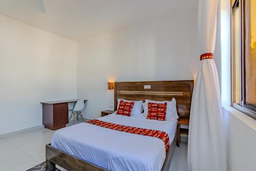 a bedroom with a bed with red pillows and a window at Wendy's Da-Azizi Homes Diani in Diani Beach