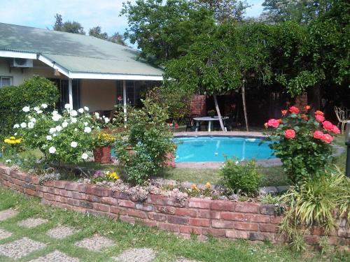 a brick retaining wall around a swimming pool with flowers at The Nook B&B in Kimberley