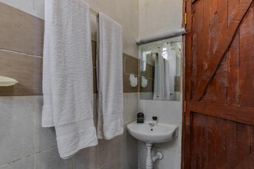 a bathroom with white towels and a sink at Wendy's Da-Azizi Homes Diani in Diani Beach