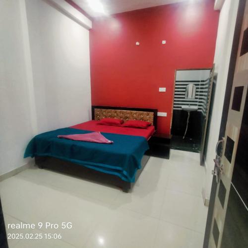 a bedroom with a bed with a red wall at Shri Prabhu guest house in Ayodhya