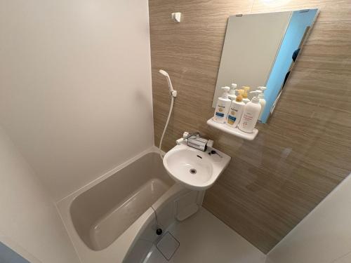 a white bathroom with a sink and a mirror at 一休居 in Osaka