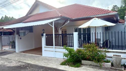 a house with a gate and an umbrella at Secret Valley near Phuket Town in Kathu