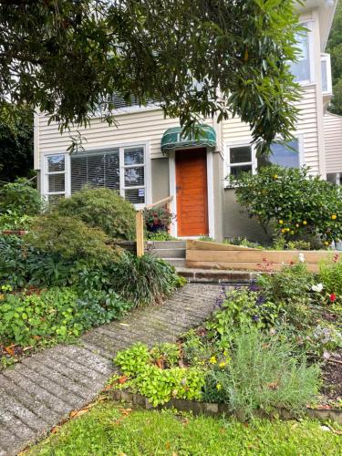 a white house with an orange door and a porch at Close To Nature & City in Wellington