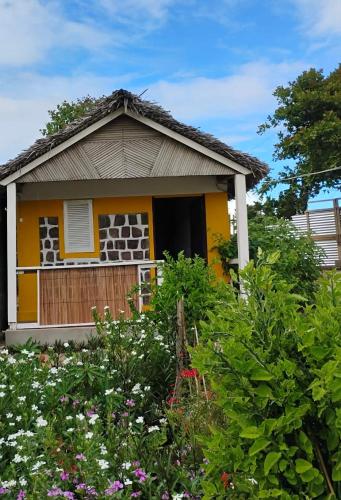 a small house with a yellow door and some flowers at MBOTY Village in Vohemar