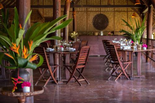 a dining room with tables and chairs and plants at The Luang Say Lodge in Pakbeng