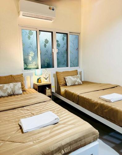 two beds sitting in a room with windows at The Best House&Hostel in Ban Don Muang (1)