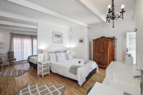 a white bedroom with a bed and a desk at Hoekkraaltjie in Yzerfontein