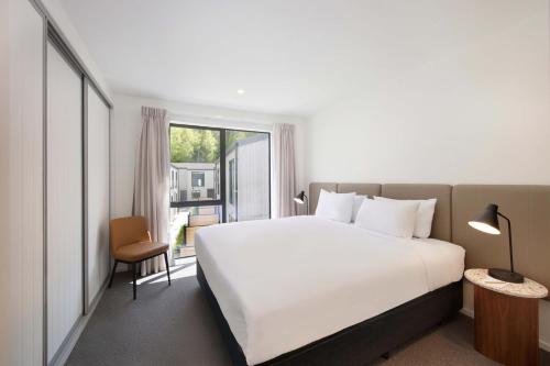 a bedroom with a large white bed and a window at Swiss-Belvillas Coronet Peak in Queenstown