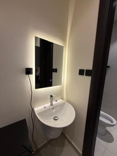 a bathroom with a sink and a mirror and a toilet at Nafel Modern Suite in Riyadh