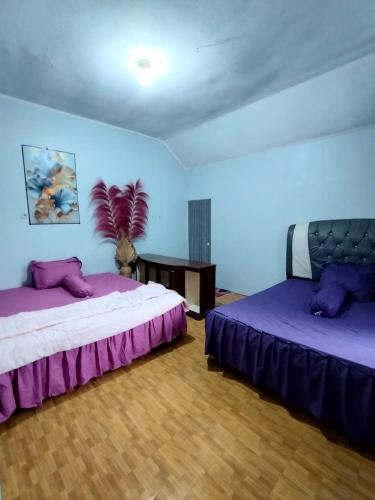 two beds in a room with purple sheets at Villa Bukit Asri Berastagi 08 in Berastagi