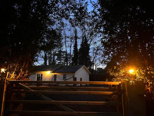 a house with a fence in front of it at night at Deandale Stays in Handforth