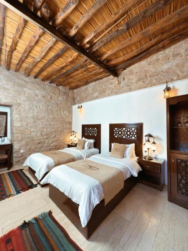 a bedroom with two beds and a stone wall at Hayat Zaman Hotel And Resort Petra in Wadi Musa