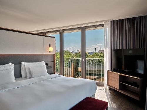 a bedroom with a large bed and a large window at Radisson Collection Hotel, Berlin in Berlin