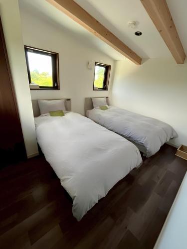 two beds in a room with two windows at ドッグラン付き一棟貸別荘- Ilio a kai イリオアカイ in Jōnouchi