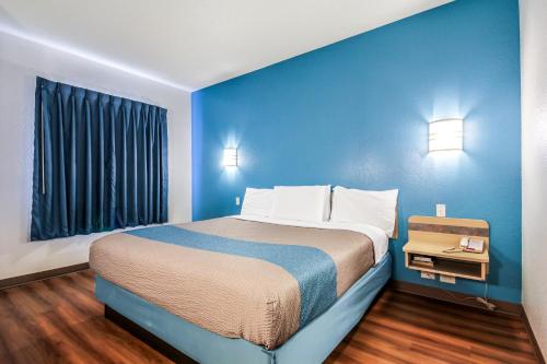 a large bed in a room with a blue wall at Motel 6 New Braunfels in New Braunfels