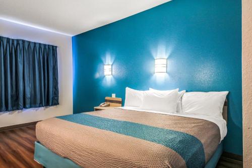 a blue bedroom with a large bed with white pillows at Motel 6 New Braunfels in New Braunfels